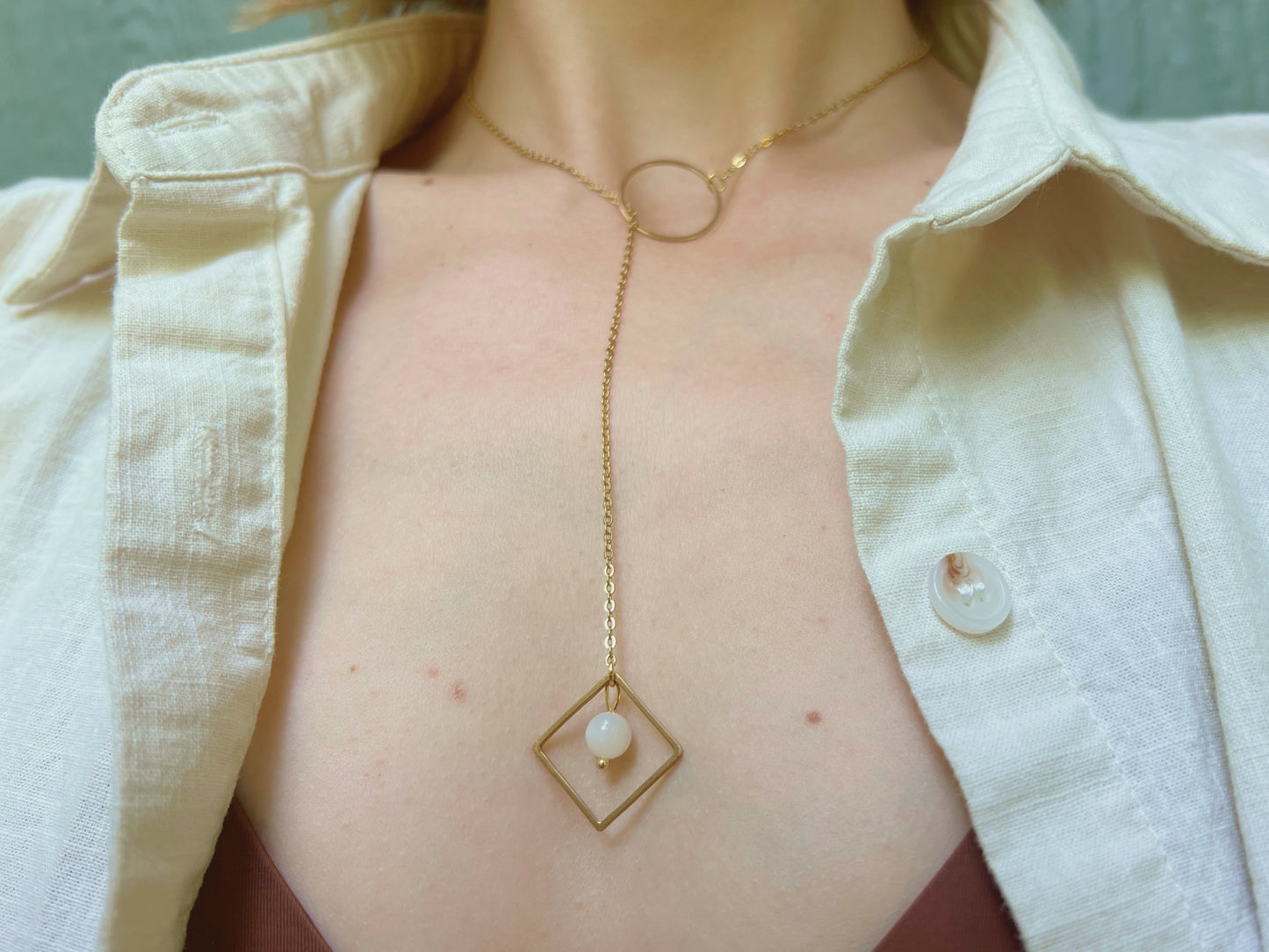 Gold lariat necklace with o ring featuring a moonstone in a square at the drop