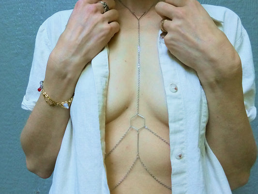 Person wearing a silver hexagonal body chain under a white shirt.