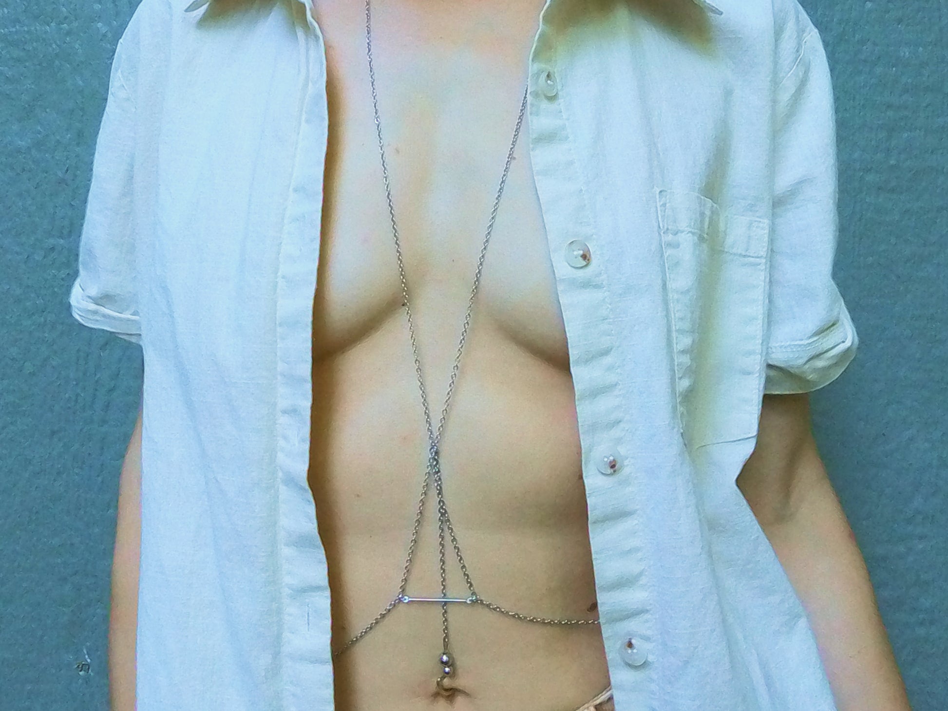 Person wearing a silver body chain bra under a white shirt