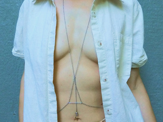 Person wearing a silver body chain bra under a white shirt