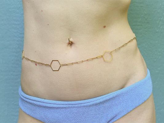 Person wearing a dainty paperclip waist chain with little polygons