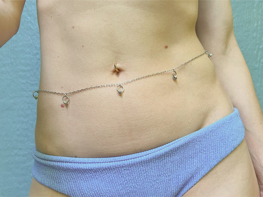 Person wearing a delicate silver waist chain with little o rings and roundel beads