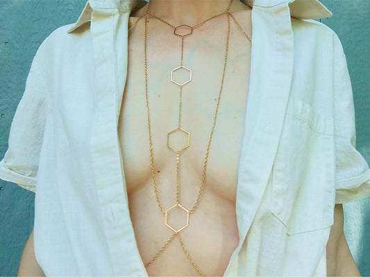 Person wearing a gold hexagonal body chain under a white shirt